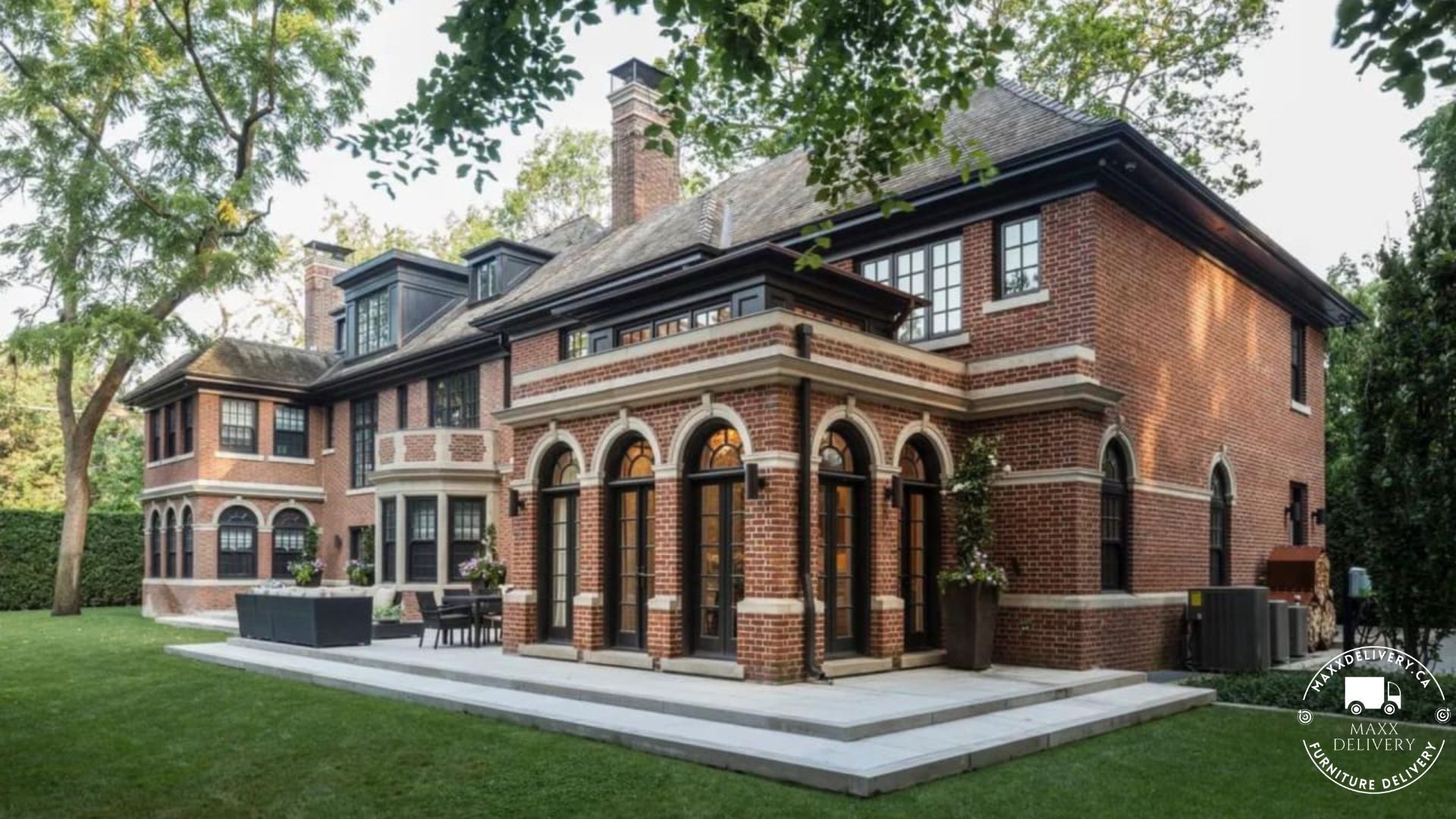 A large brick house with arched windows and a patio in front of it.