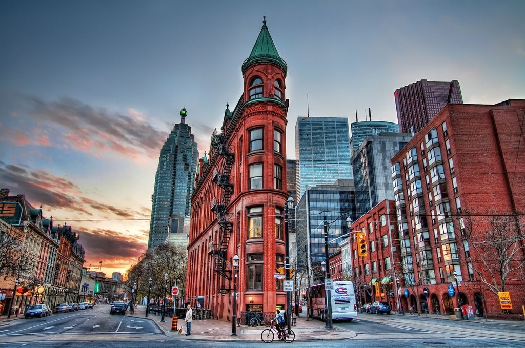 A brick building with a green roof sits on the corner of a city street