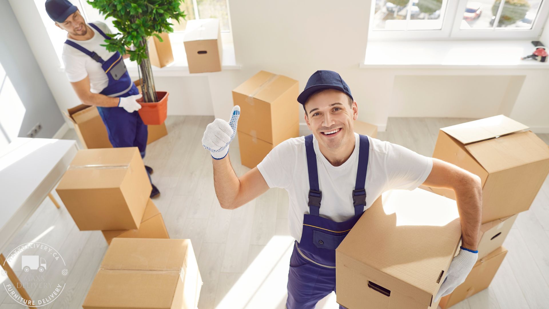 A man is holding a cardboard box in a room with other boxes