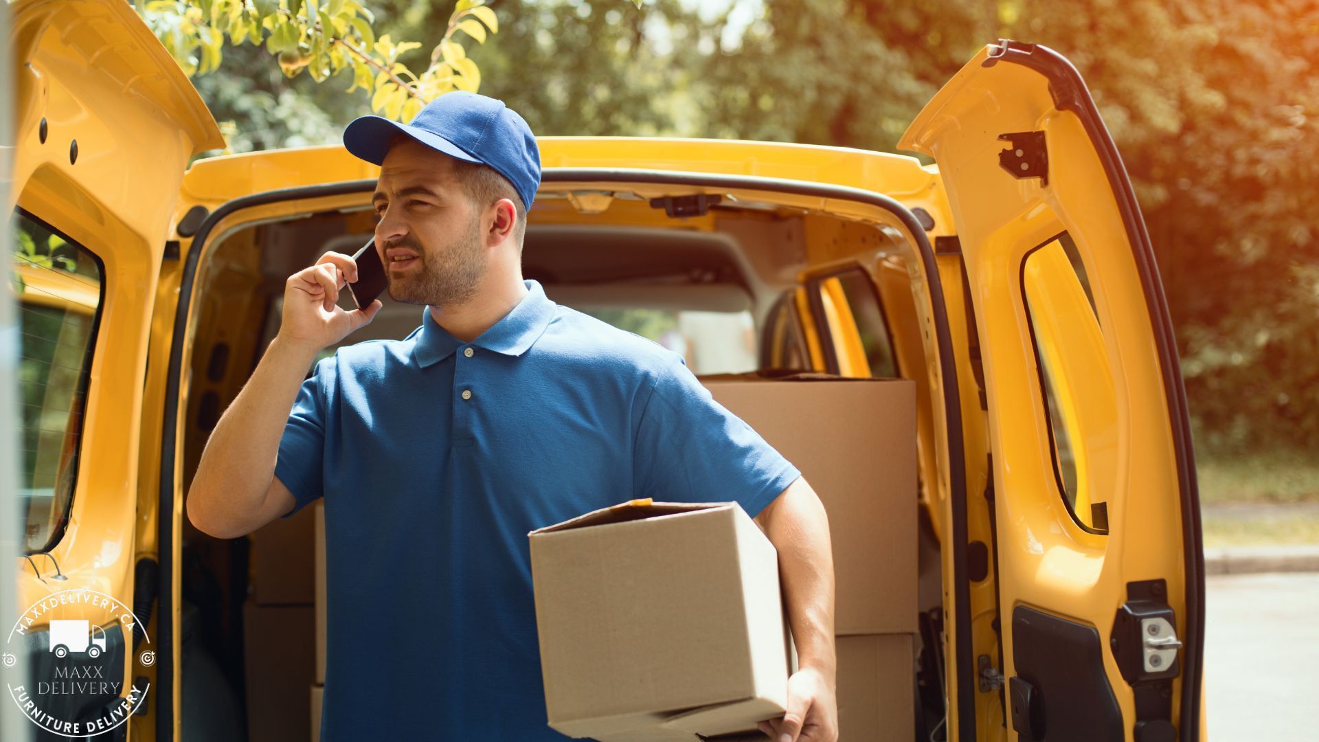 A delivery man is talking on a cell phone while holding a box