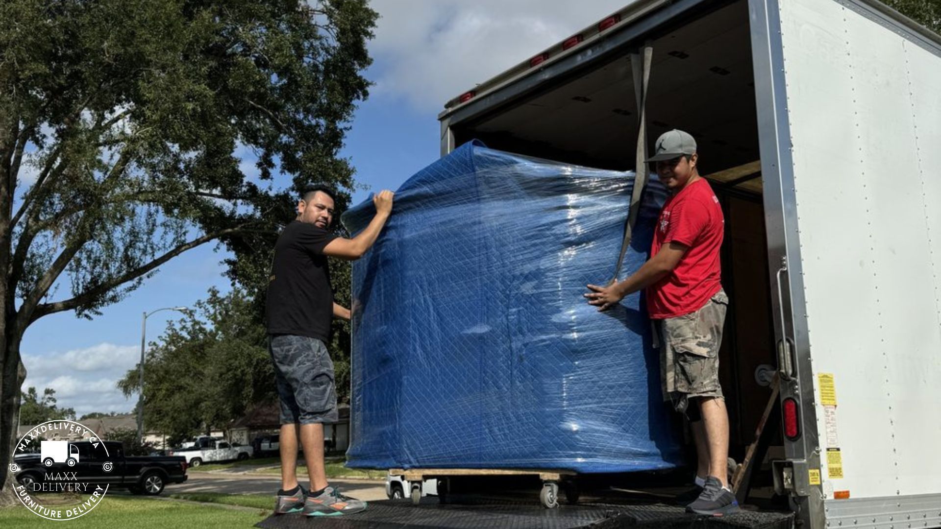 Two men are moving a large appliance from a 15 Ft Moving truck - Appliance delivery in Toronto and GTA