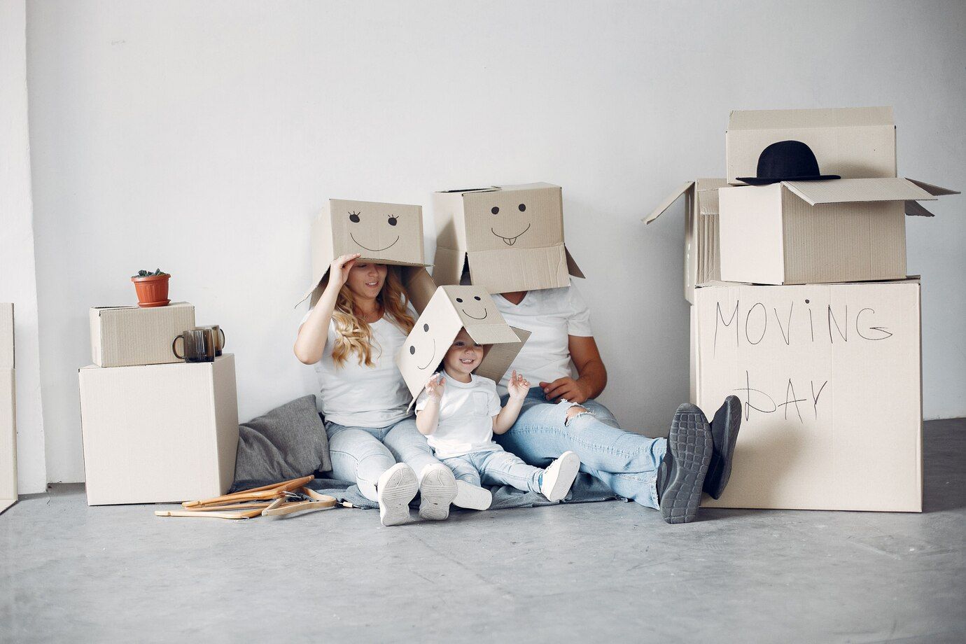 A family is sitting on the floor with cardboard boxes on their heads.