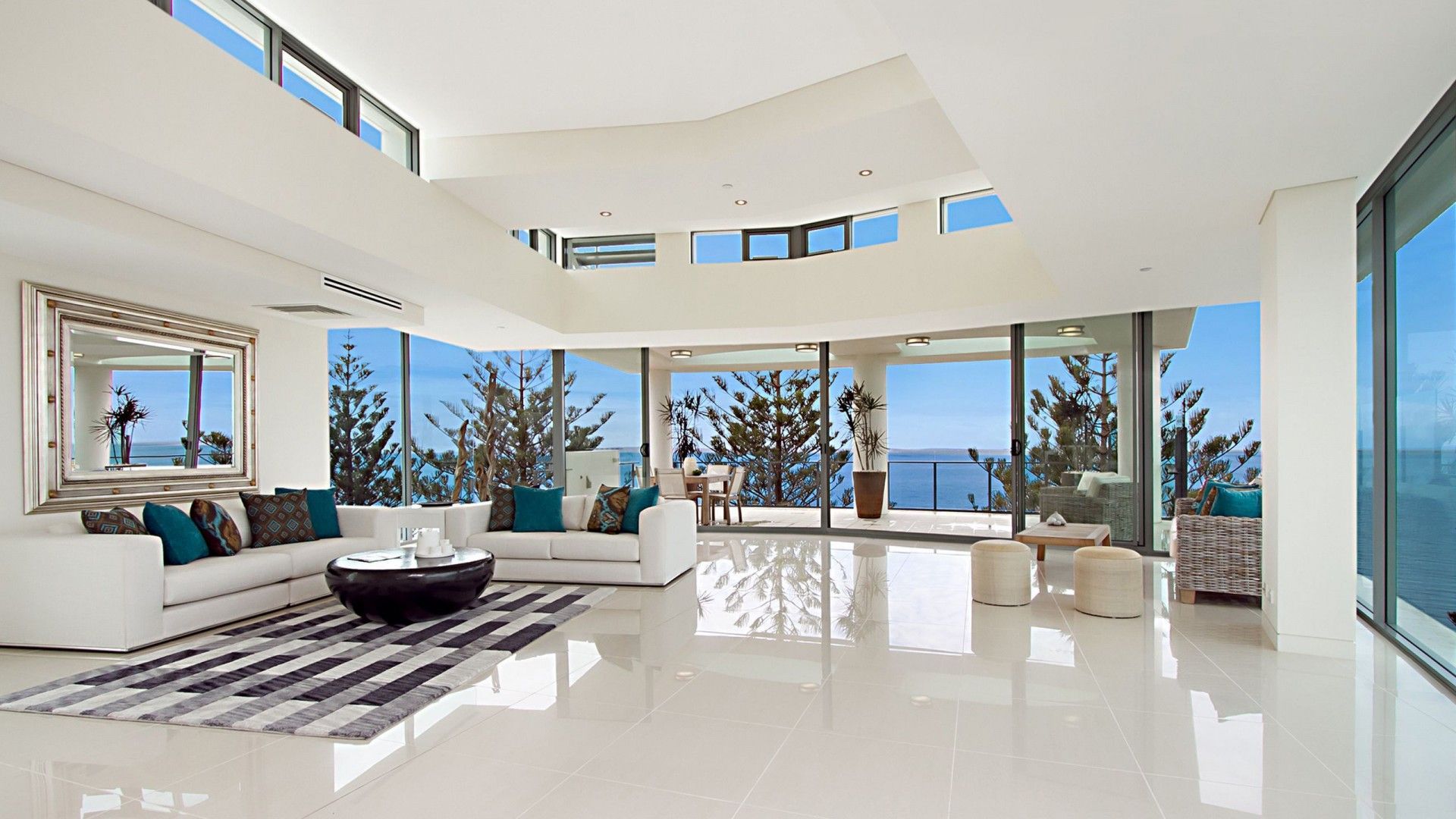 A living room with a lot of windows looking out to the ocean