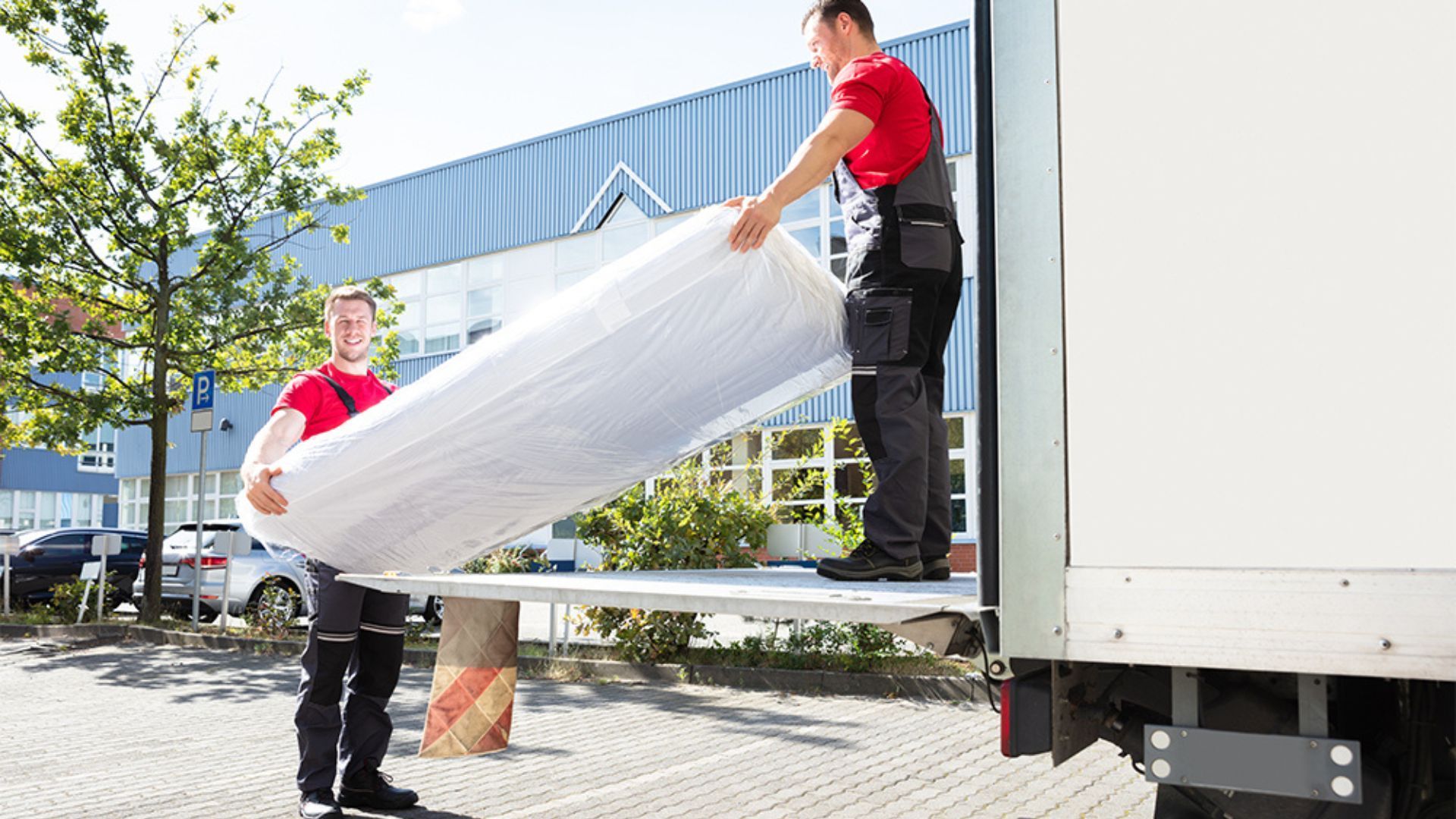 Two men are loading a mattress into a truck