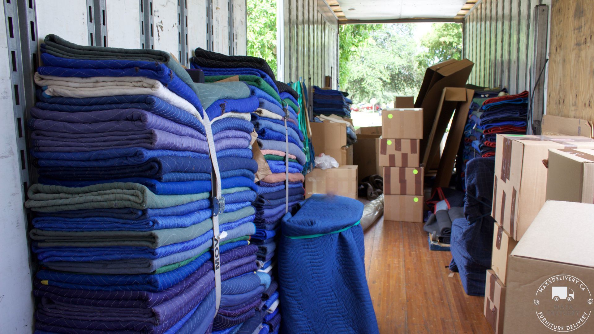 The inside of a moving truck filled with blue blankets and boxes