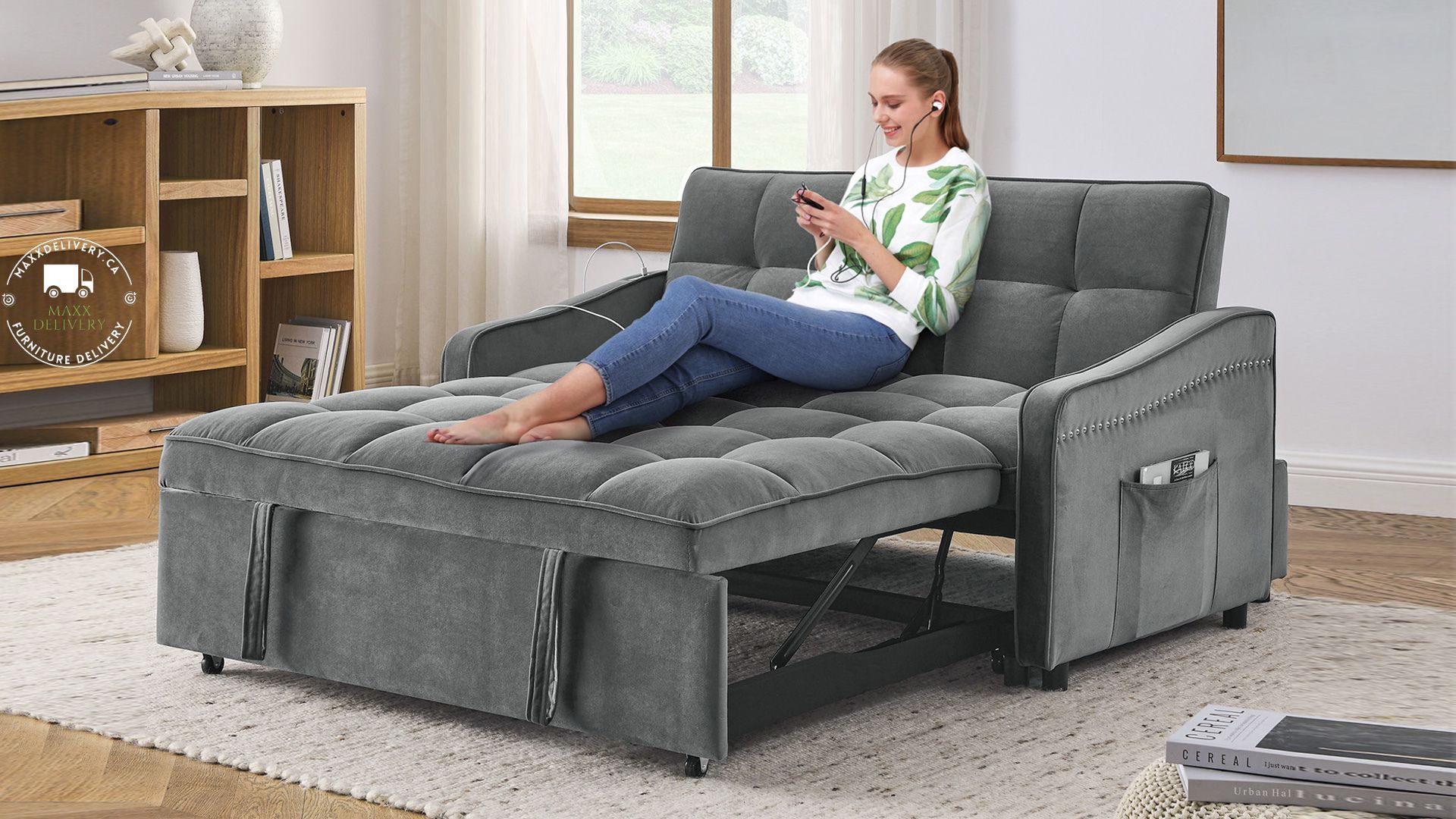 A woman is sitting on a couch that has been converted into a bed.