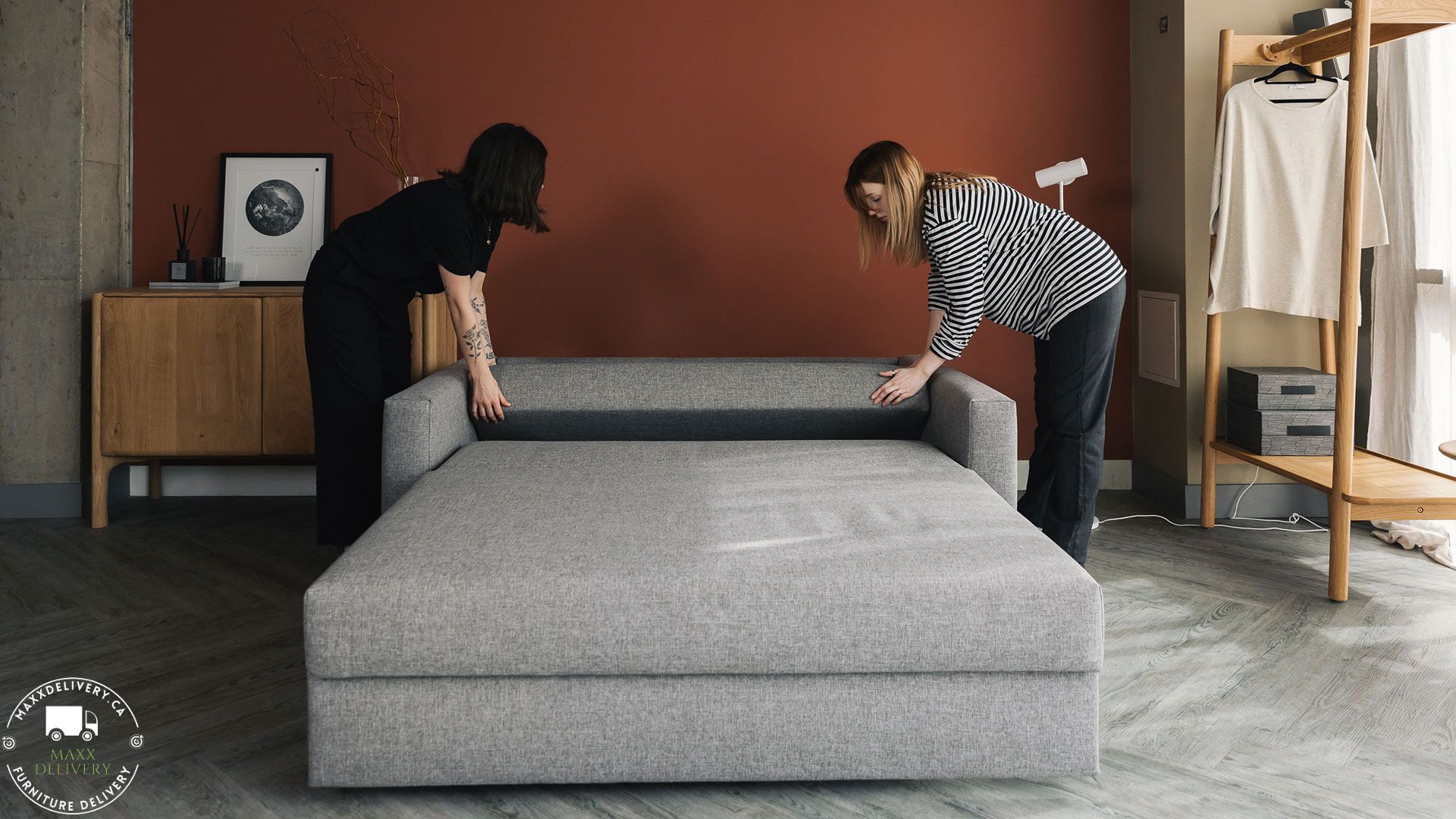 Two women are bending over a couch in a living room