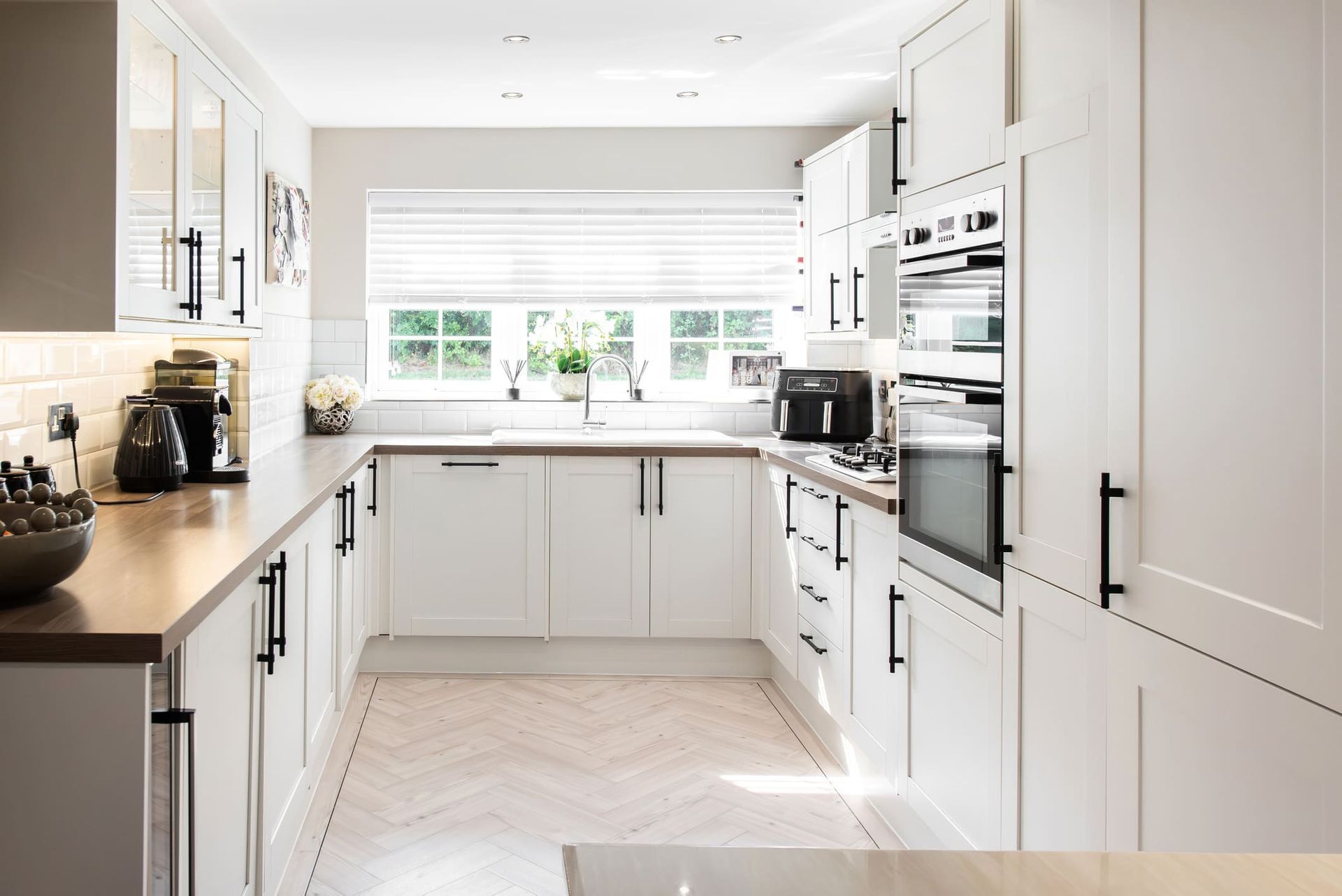 A kitchen with white cabinets , wooden counter tops , and stainless steel appliances.