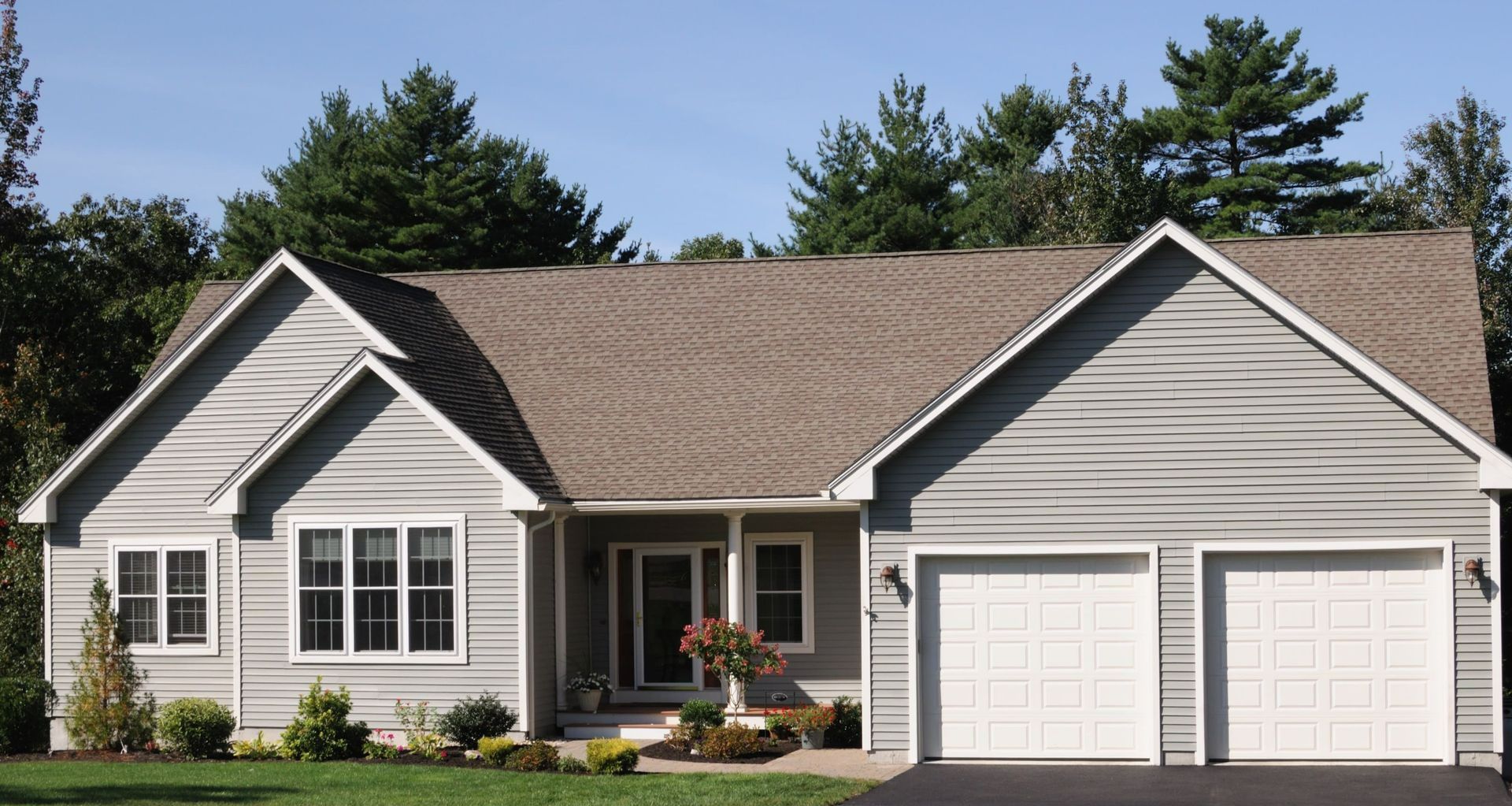 A house with two garage doors and a brown roof