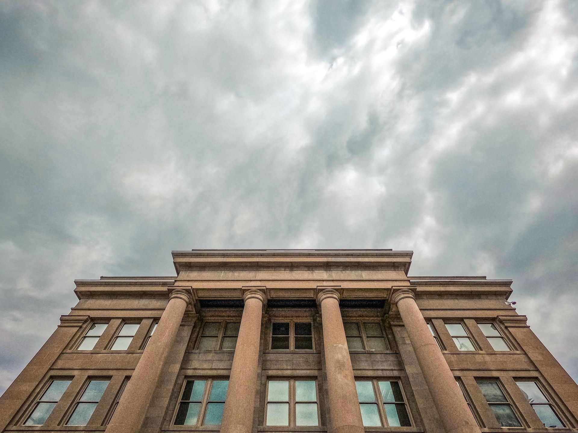 Looking up at a large building with columns on a cloudy day