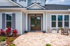 The front of a house with a patio and chairs in front of it.