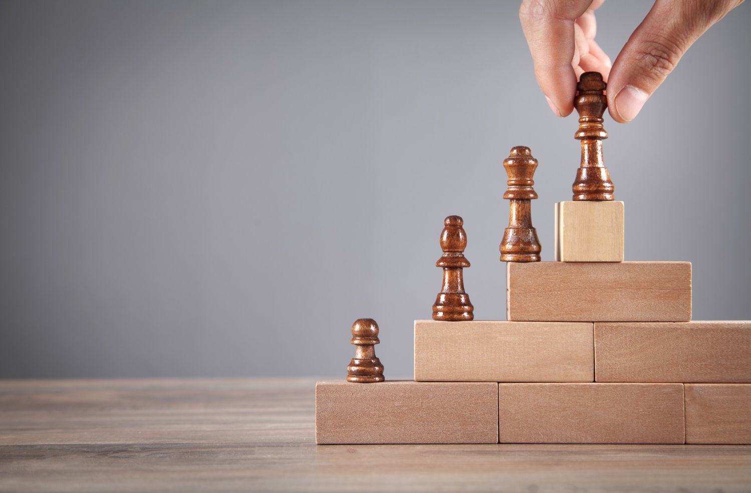 Una persona está colocando una pieza de ajedrez encima de una pila de bloques de madera.