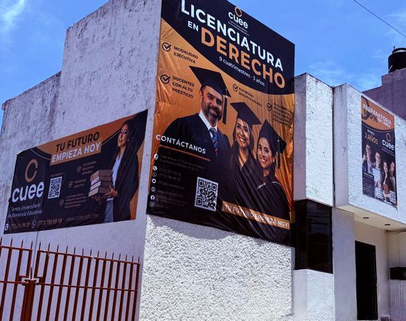 Un gran edificio con una bandera en la parte superior está rodeado de árboles.