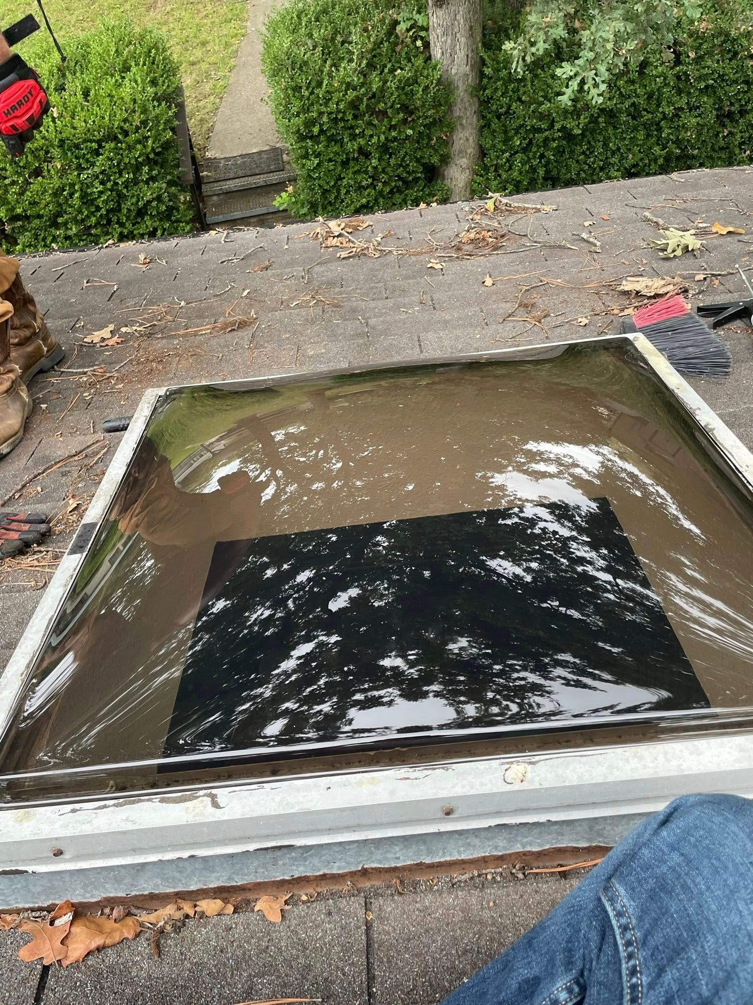 Skylight on a rooftop filled with water, surrounded by debris.