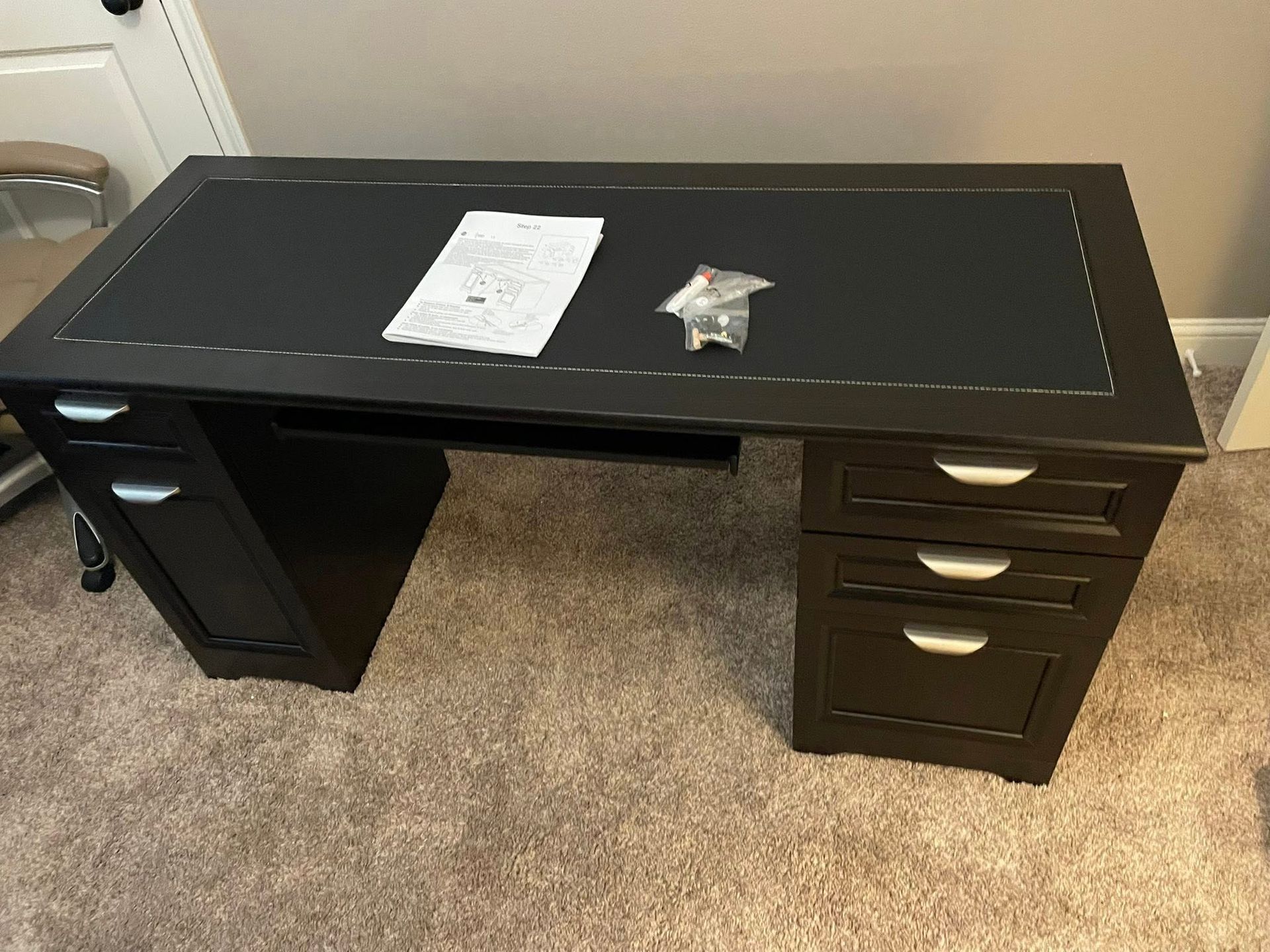 Black desk with drawers and a dark tabletop; paperwork and hardware are on top.