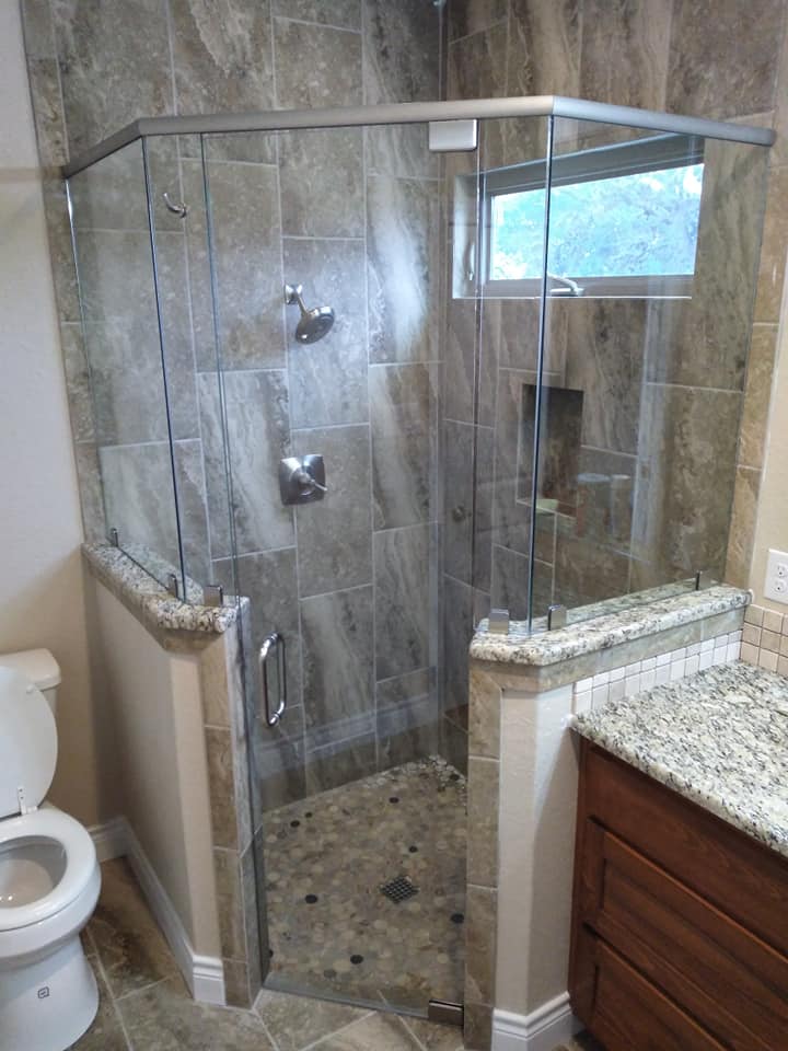 A bathroom with a toilet and a shower stall with sliding glass doors.