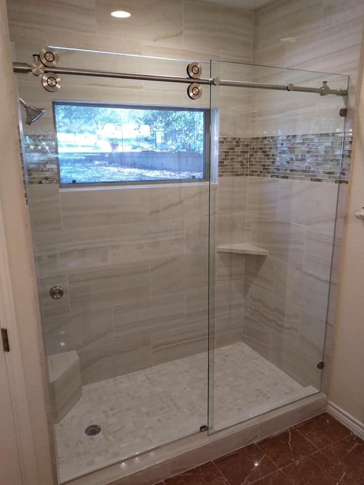 A bathroom with a sliding glass shower door and a window.