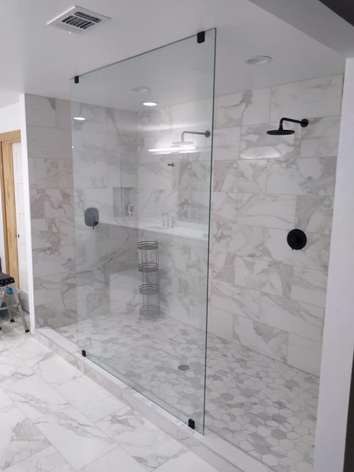 A bathroom with marble tiles and a walk in shower with a glass door.