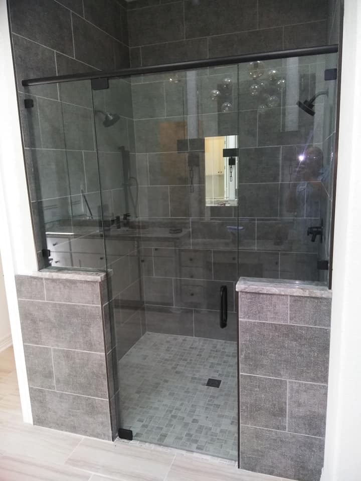 A bathroom with a walk in shower with a glass door.