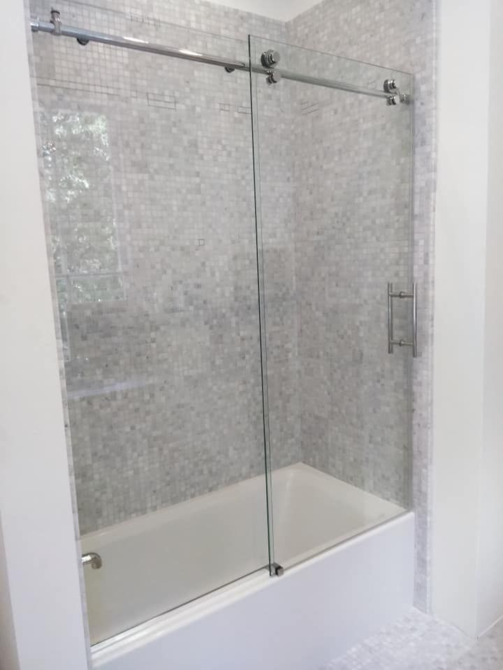 A bathroom with a bathtub and a sliding glass shower door.