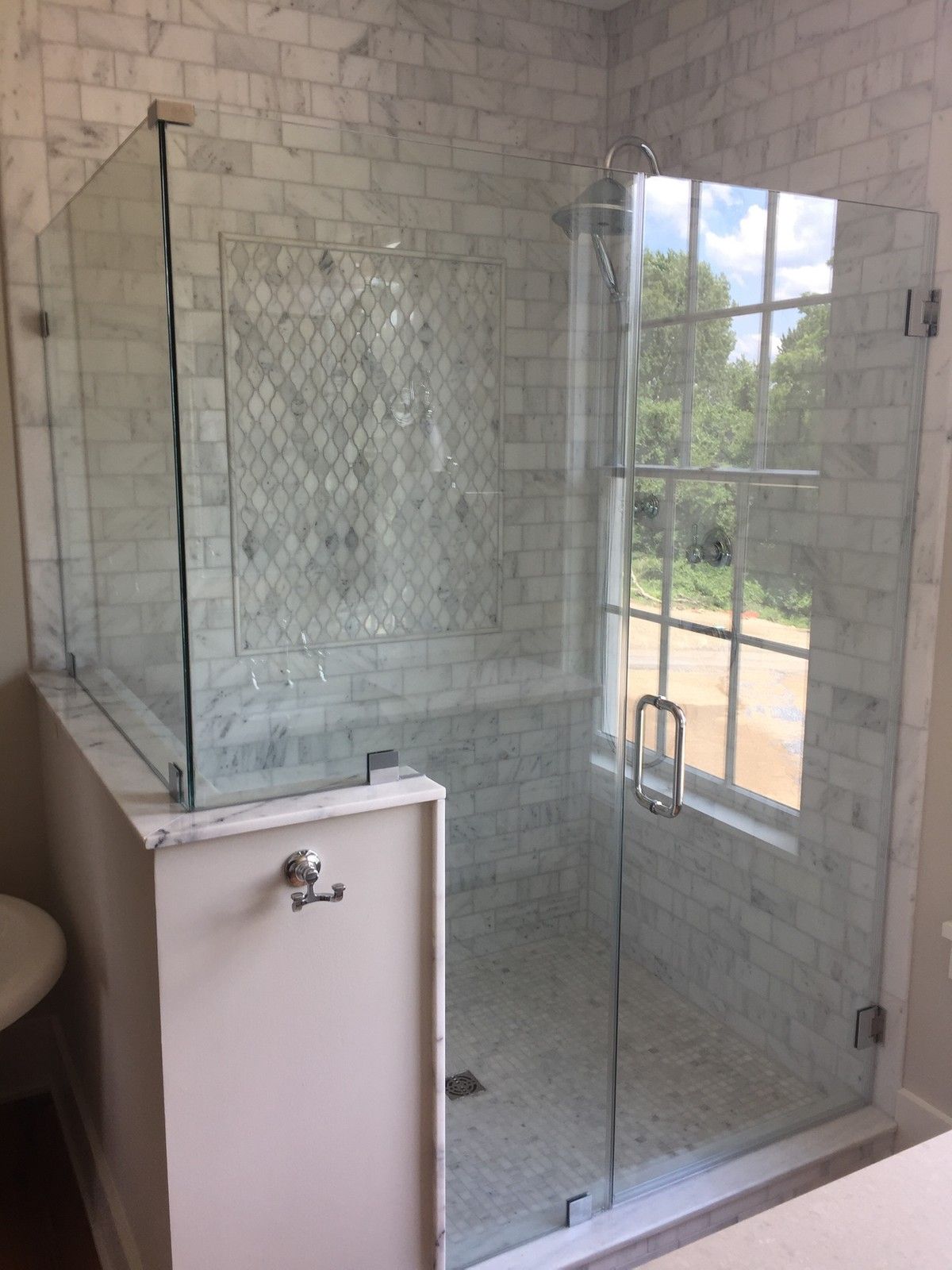 A bathroom with a glass shower door and a window.