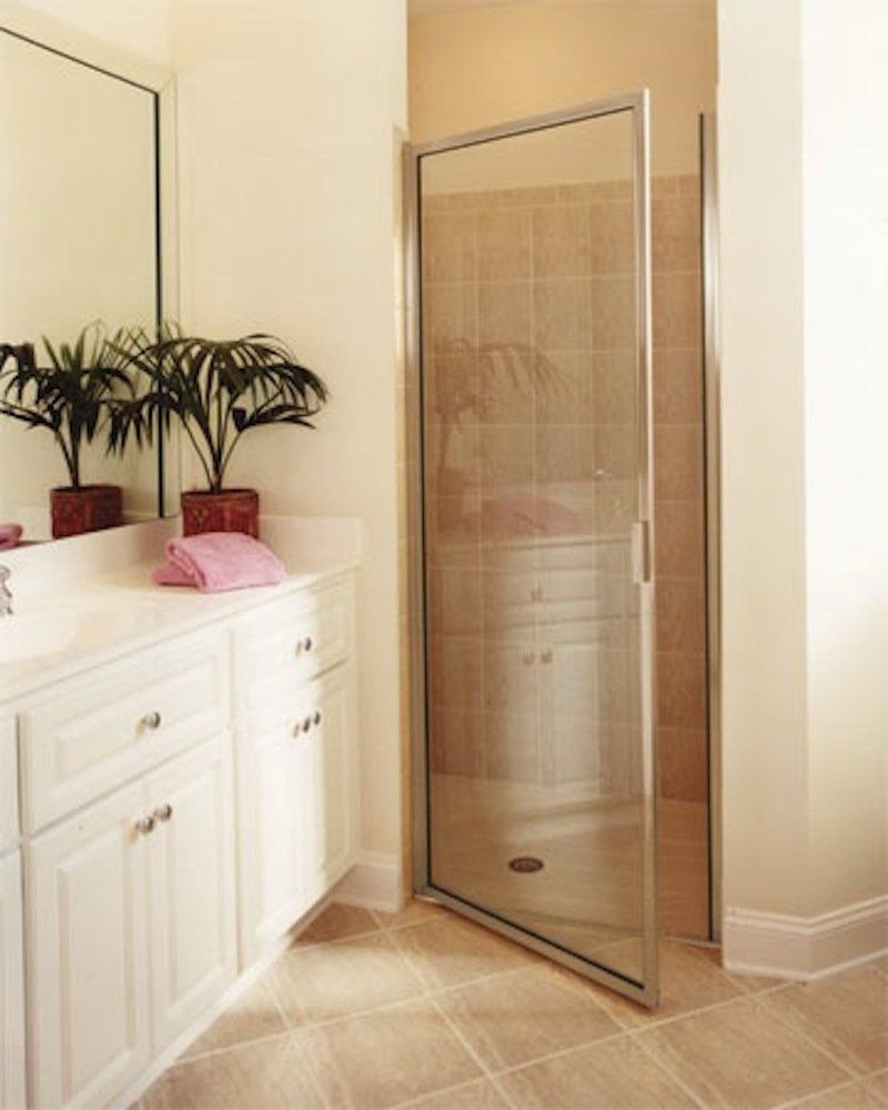 A bathroom with white cabinets and a glass shower door