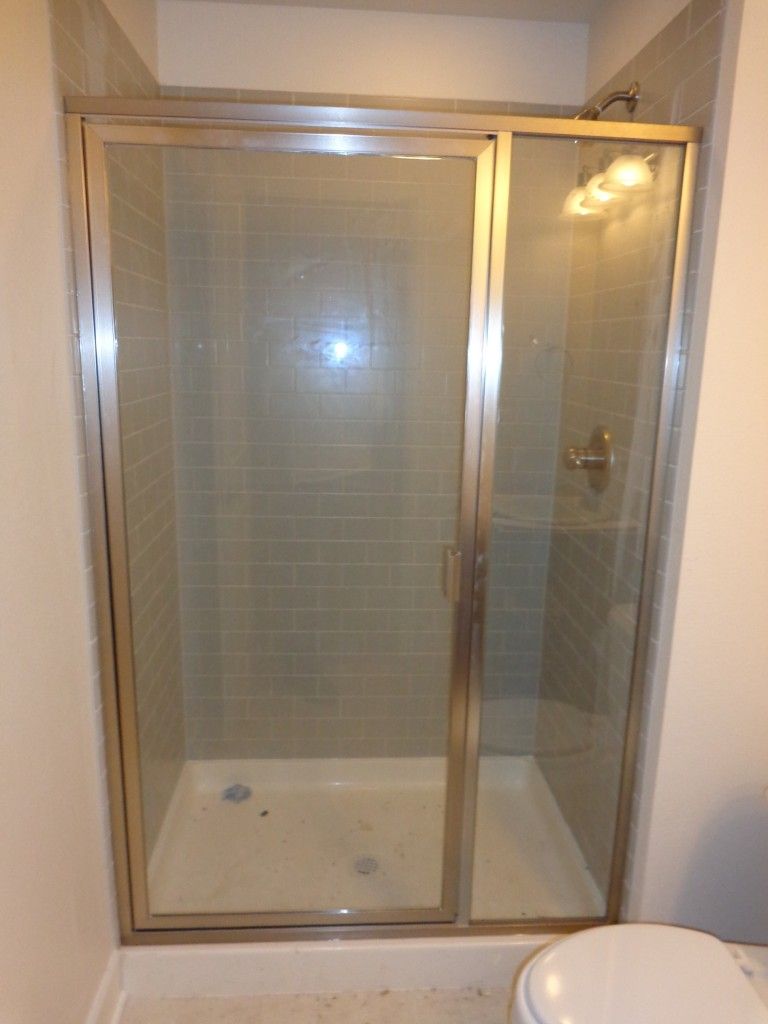 A bathroom with a sliding glass shower door and a toilet
