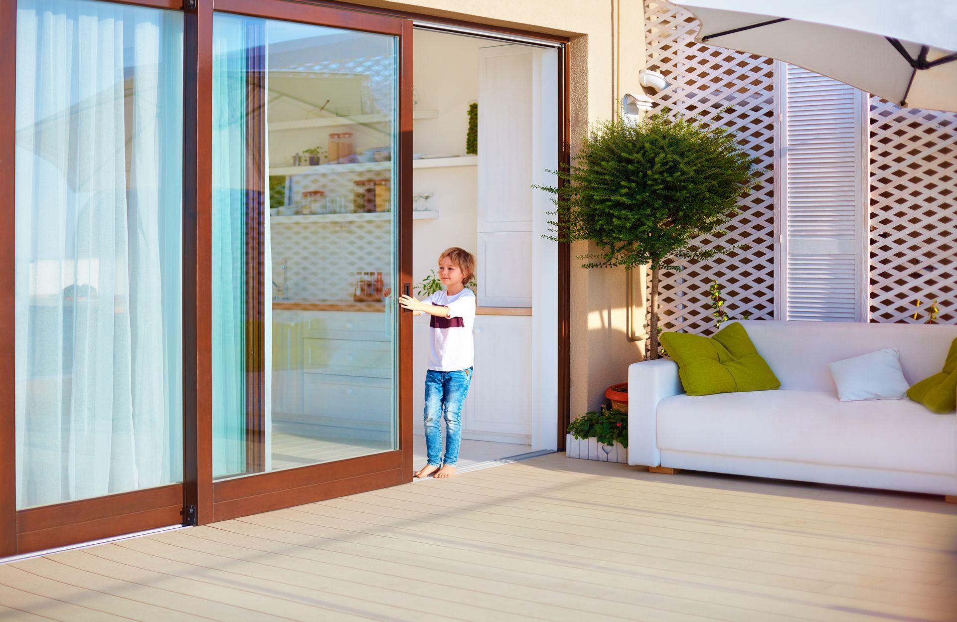 A little boy is standing in front of a sliding glass door.