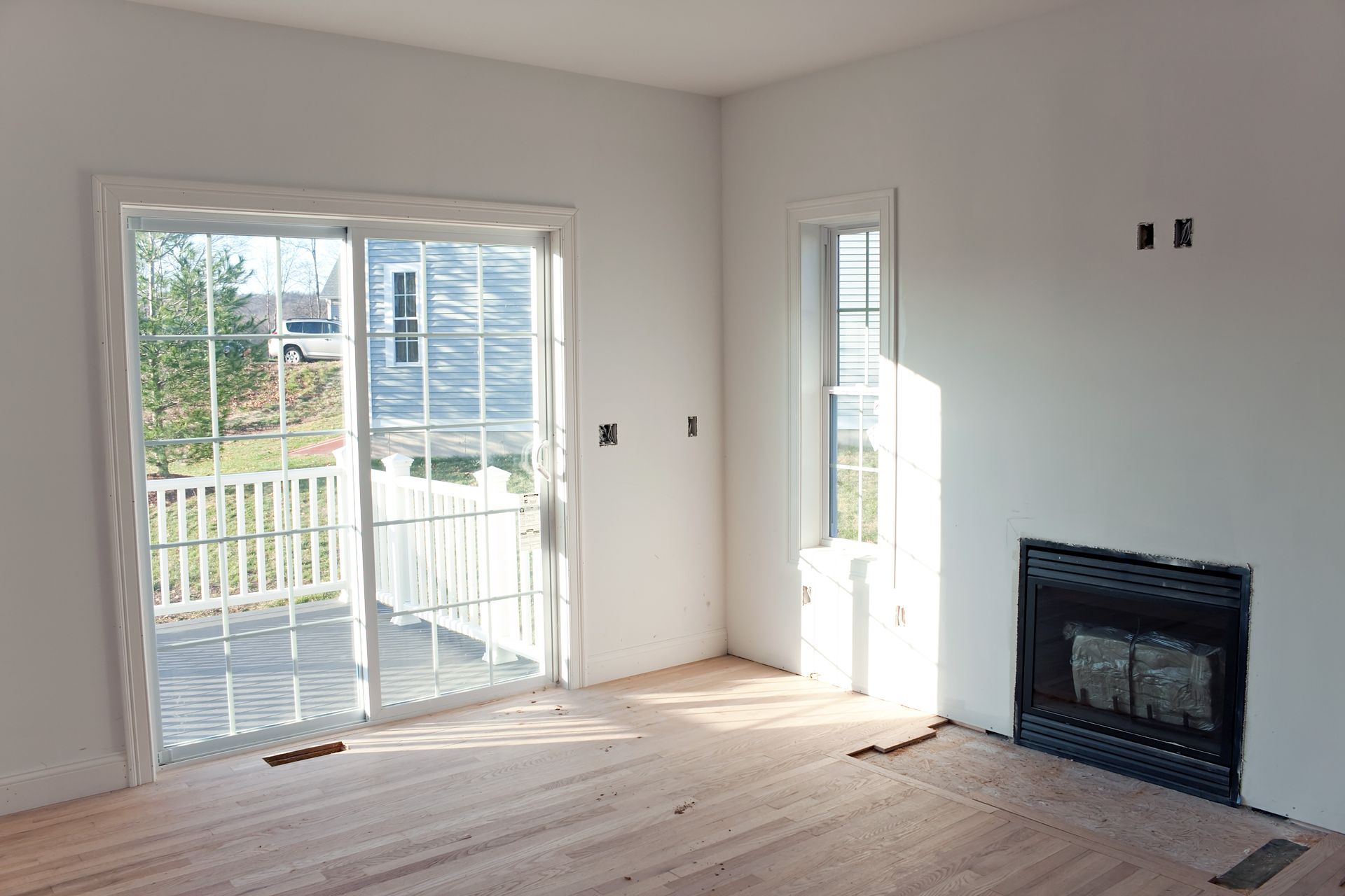An empty living room with a fireplace and sliding glass doors.