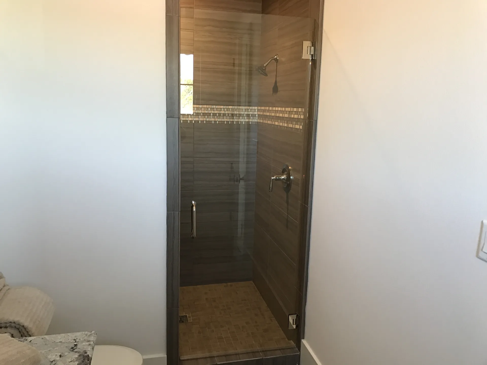 A bathroom with a glass shower door and a toilet.