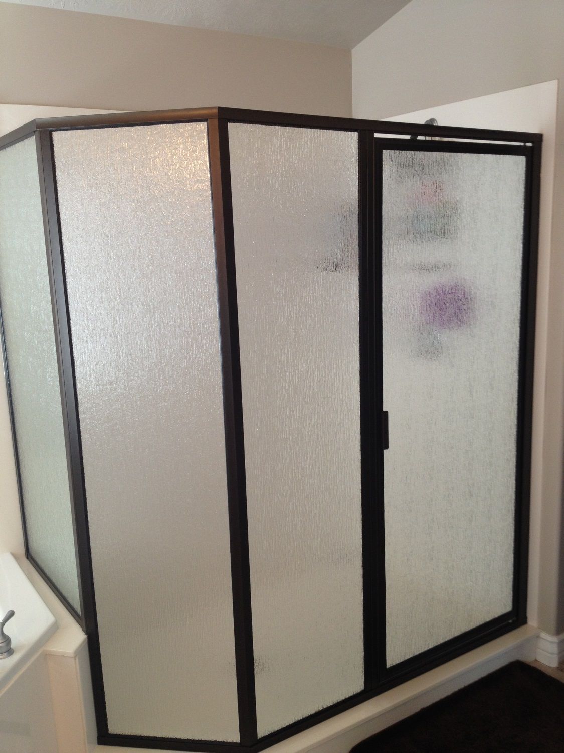 A shower stall with frosted glass and a black frame