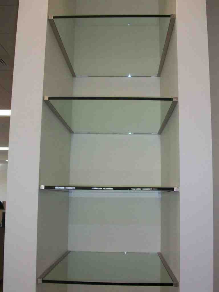 The shelves are made of glass and metal and are empty
