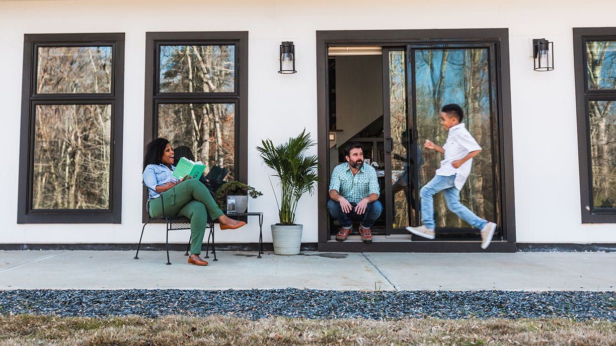 A family is sitting on a porch in front of a house.