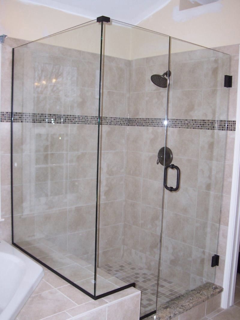 A bathroom with a walk in shower with a black handle