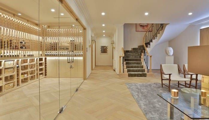 A living room with a glass wall and a wine cellar.