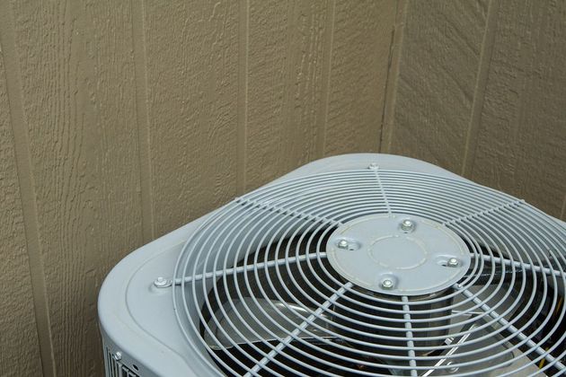 A white air conditioner is sitting in the corner of a room.
