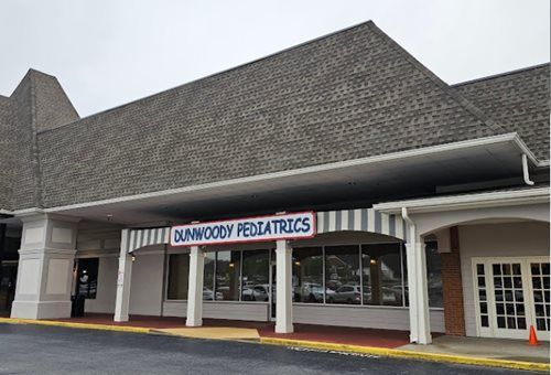 Dunwoody Pediatrics storefront with sign, awning, and parking area.