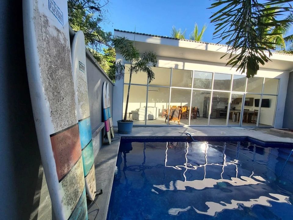 A surfboard is leaning against a wall next to a swimming pool