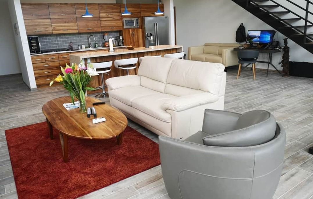 A living room with a couch , chair , coffee table and stairs.