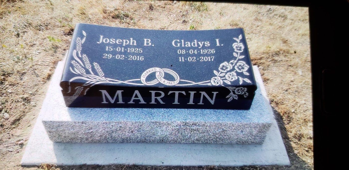 A black granite headstone engraved with names, dates, and 