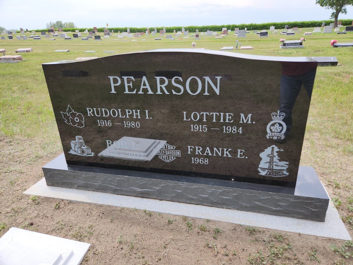 Black granite headstone in a cemetery with the name Pearson and names and dates for three people.