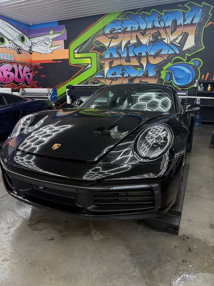 Black Porsche 911 in a garage with graffiti art on the wall.