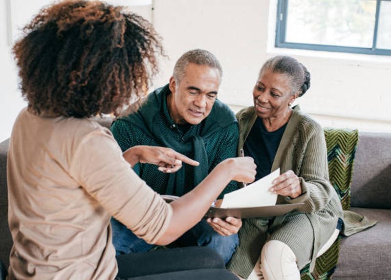Financial advisor showing document to couple on a couch.