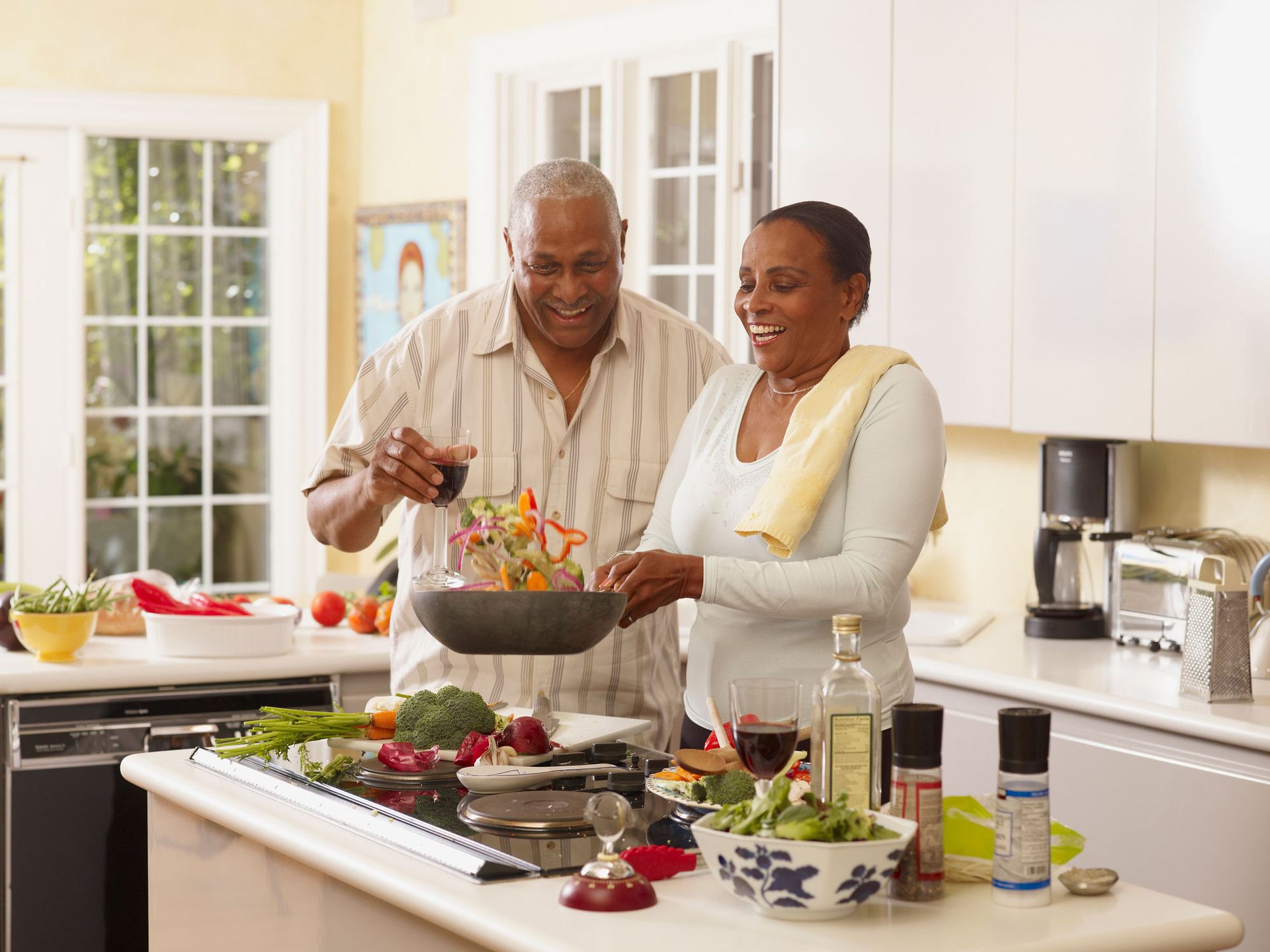 Couple cooking together in a bright kitchen, smiling, stir-frying vegetables.