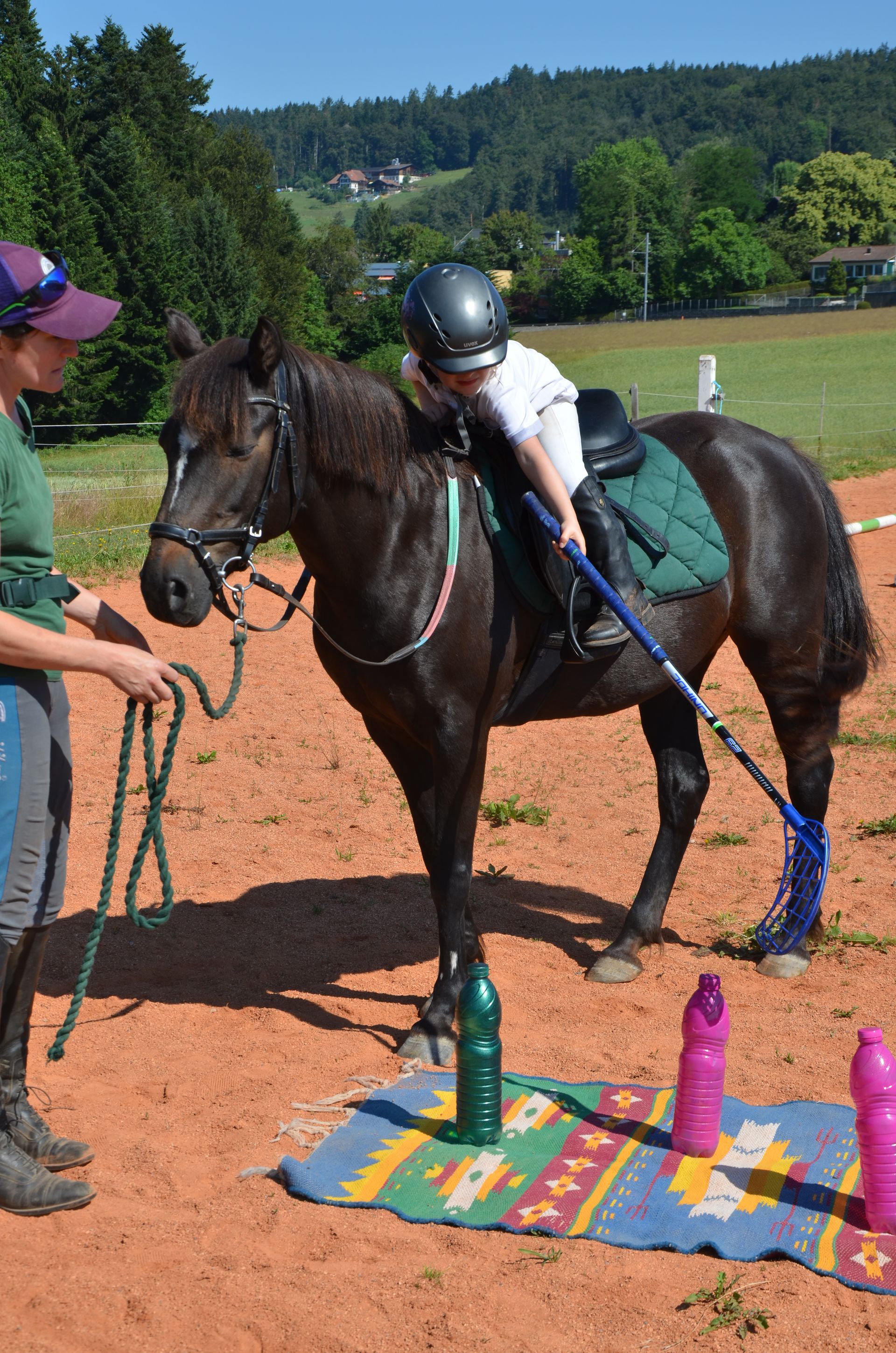 Ein kleines Kind reitet auf einem schwarzen Pferd über ein Feld.