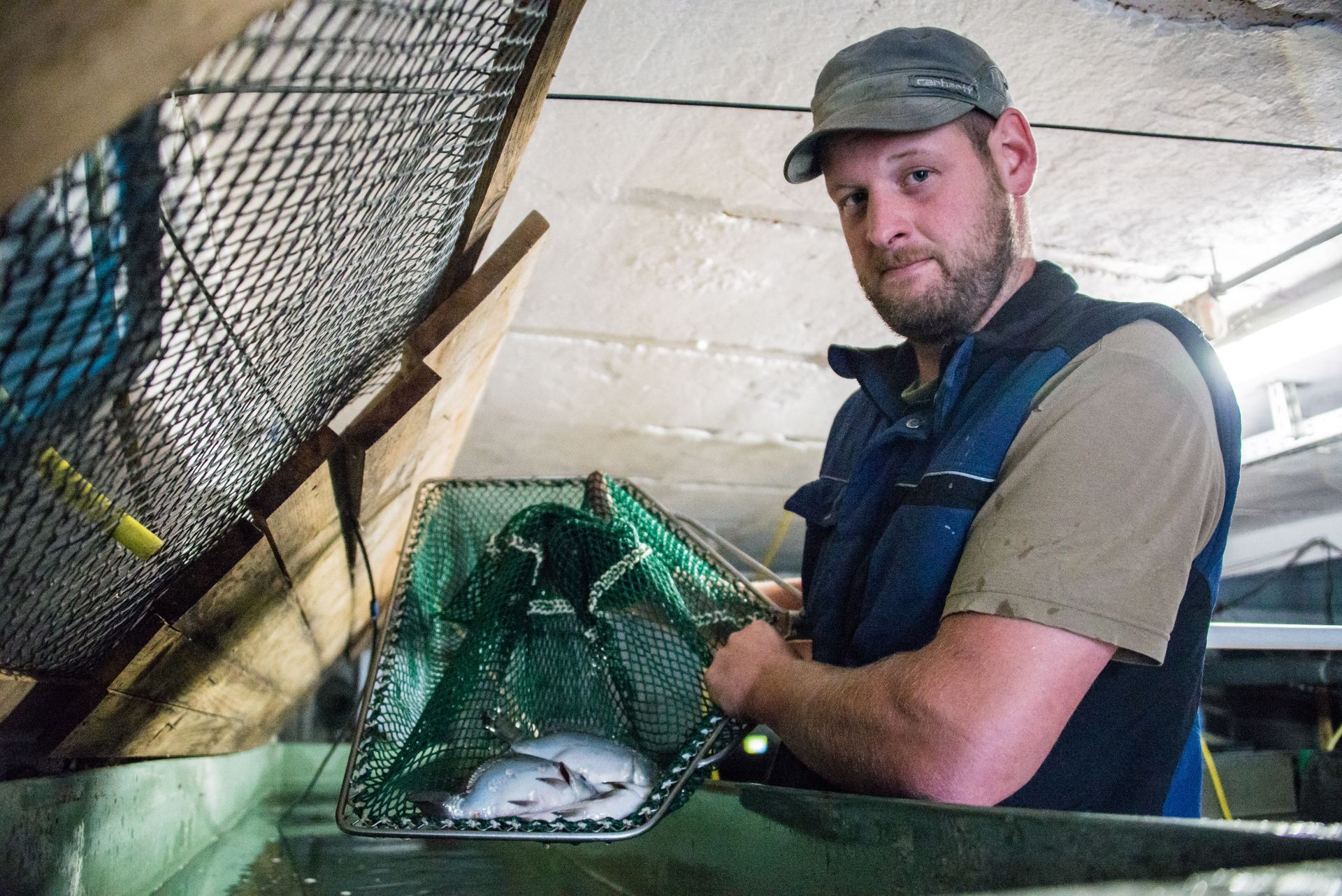 Ein Mann hält ein Fischernetz mit einem Fisch darin.