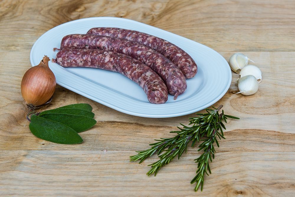 Ein weißer Teller mit Würstchen und Zwiebeln auf einem Holztisch.