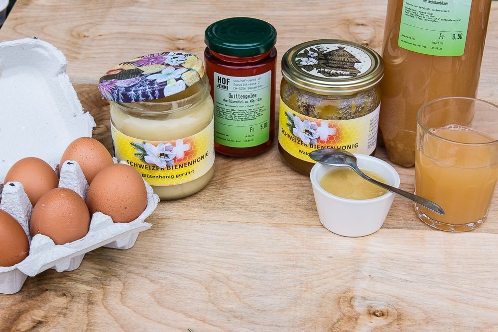 Ein Holztisch mit Eiern, Gläsern mit Honig und einem Glas Saft.