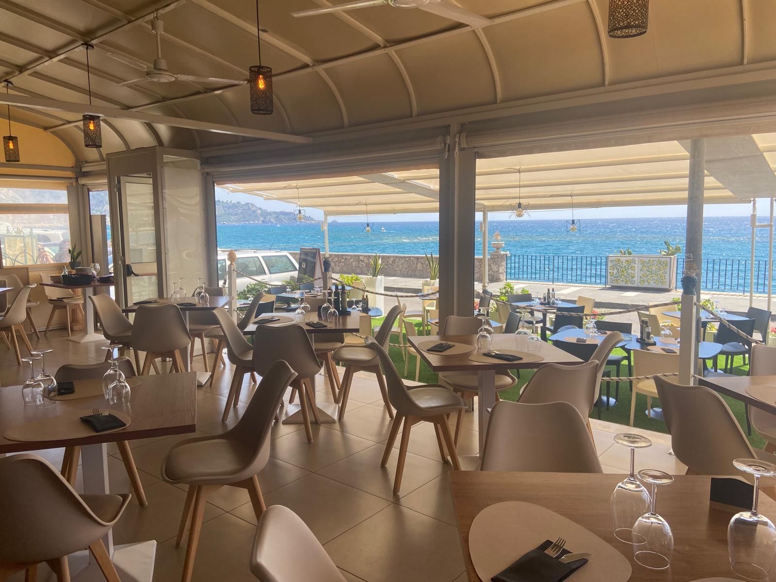 Un ristorante con tavoli e sedie e vista sul mare.