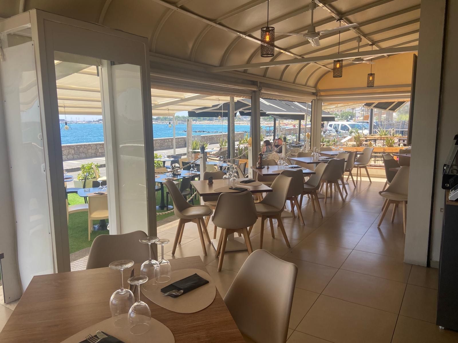 Un ristorante con tavoli e sedie e vista sul mare.